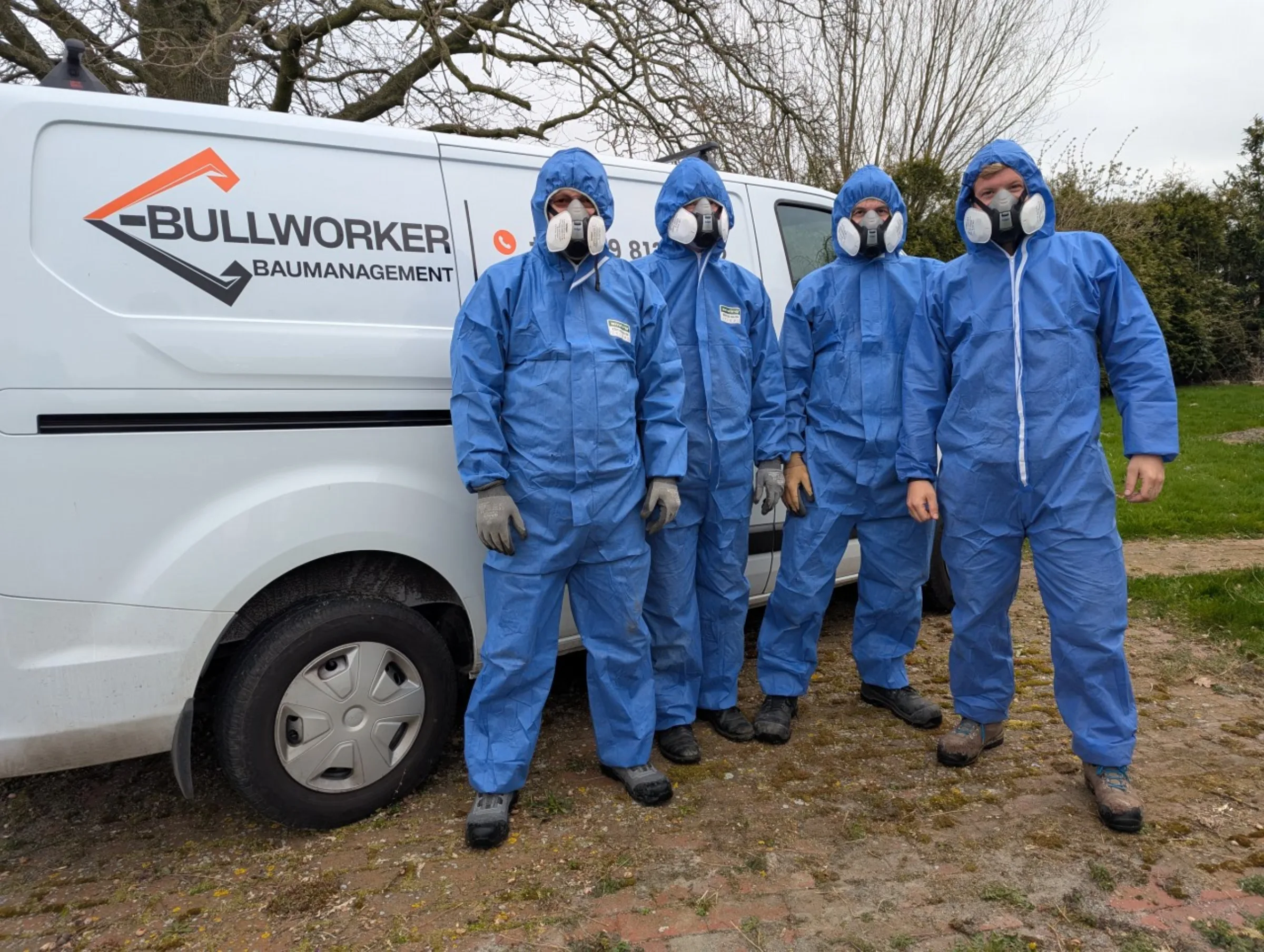 Team von Bullworker-Tiefbau in Schutzausruestung vor dem Firmen-Transporter